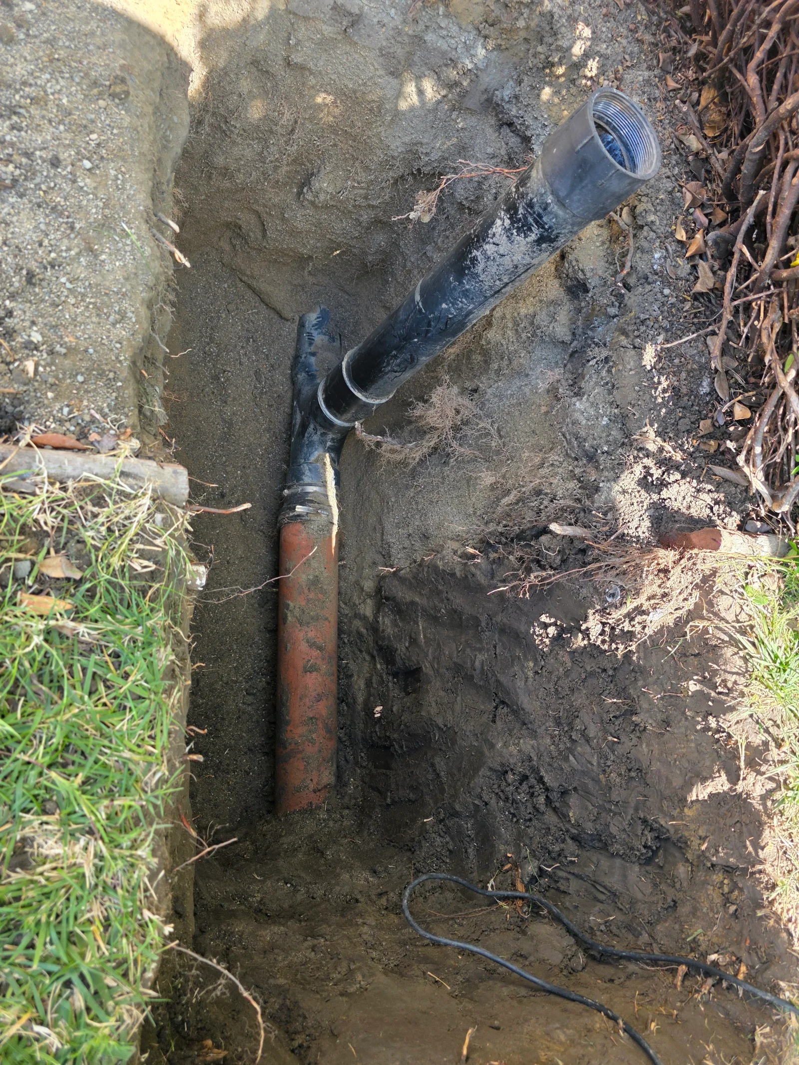 Black polyethylene gas line with brass fittings installed in underground trench
